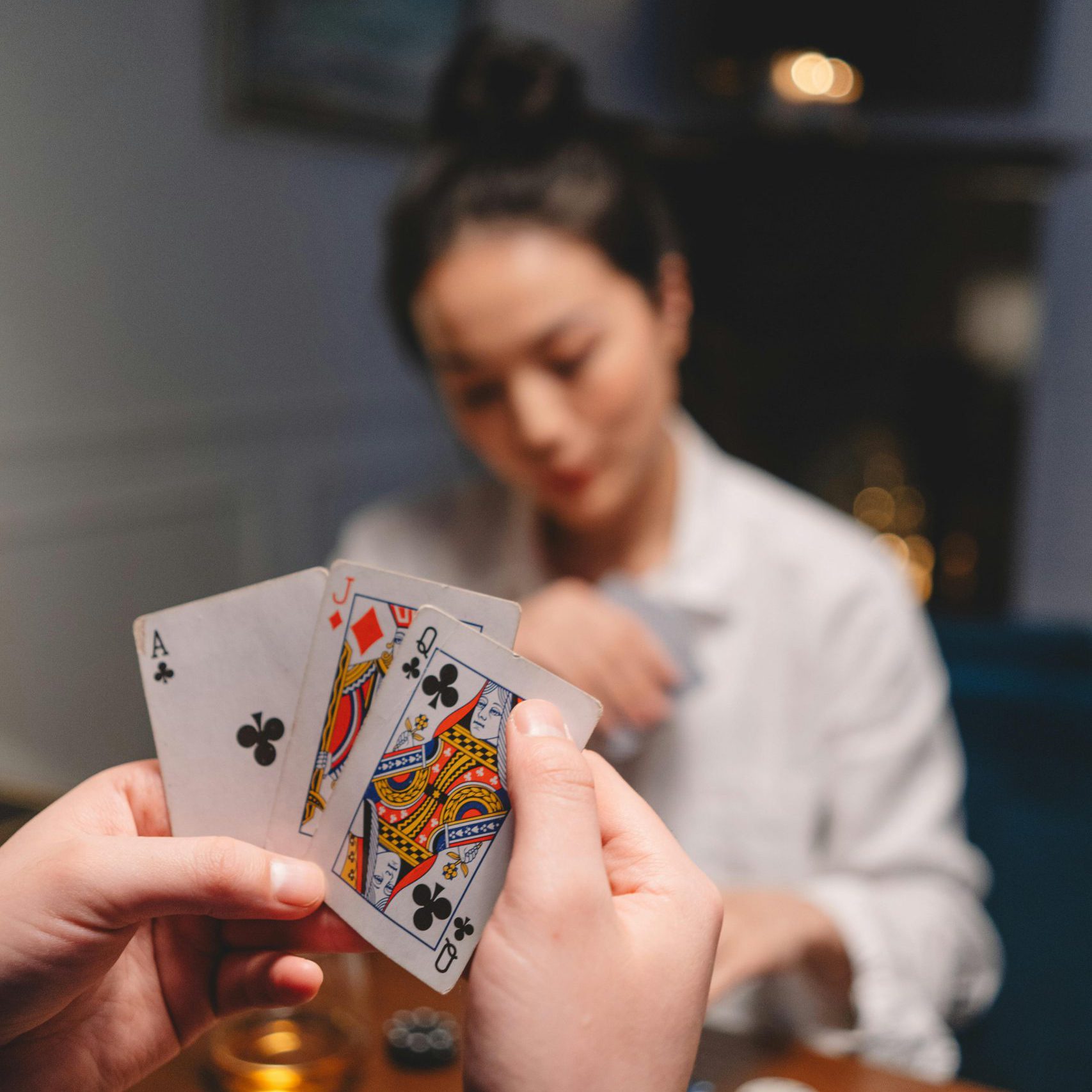 Focused close-up of a person holding cards during a poker game with a blurred background.